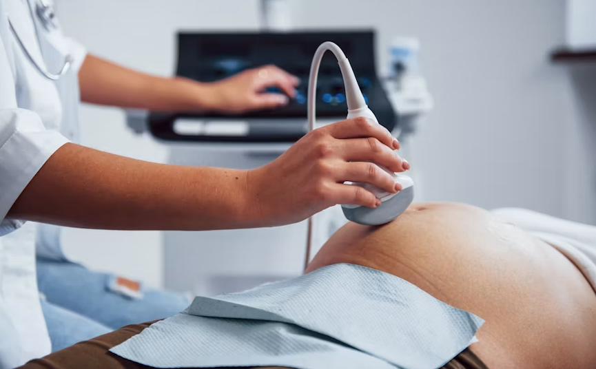 Nurse using handheld ultrasound tech during a patient checkup